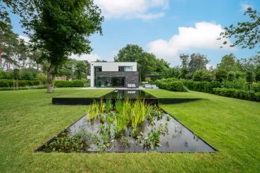 Moderne villa met groene tuin, inclusief ruim terras en overloopzwemvijver.