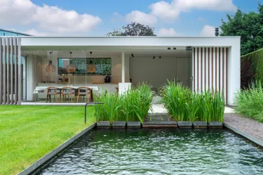 Modern poolhouse met keuken, eethoek en lounge aan zwemvijver